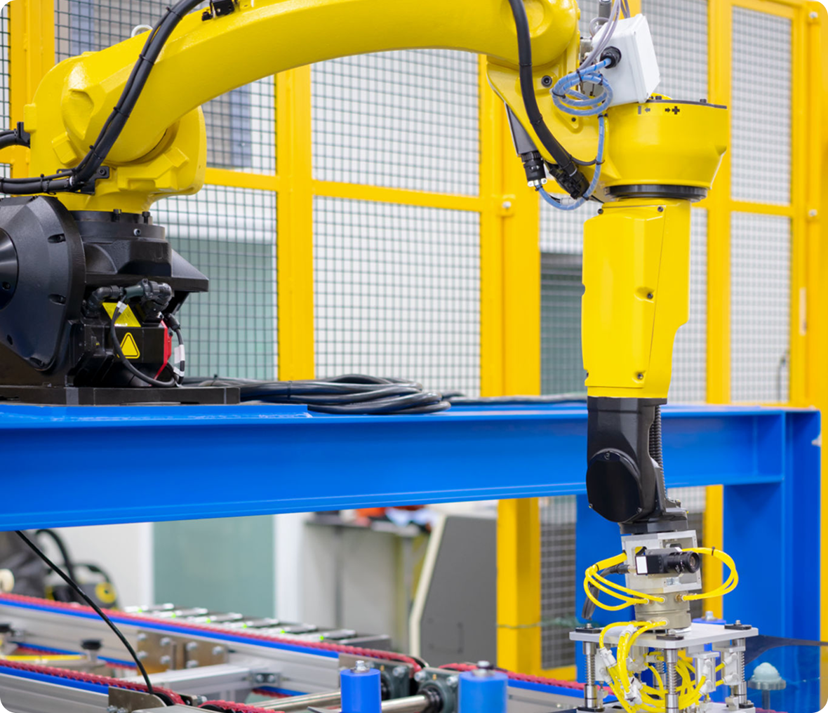 A yellow industrial robot arm assembling parts in a factory setting.