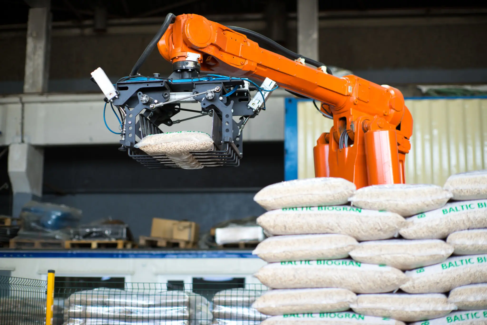 Orange robotic arm handling sacks in a warehouse.
